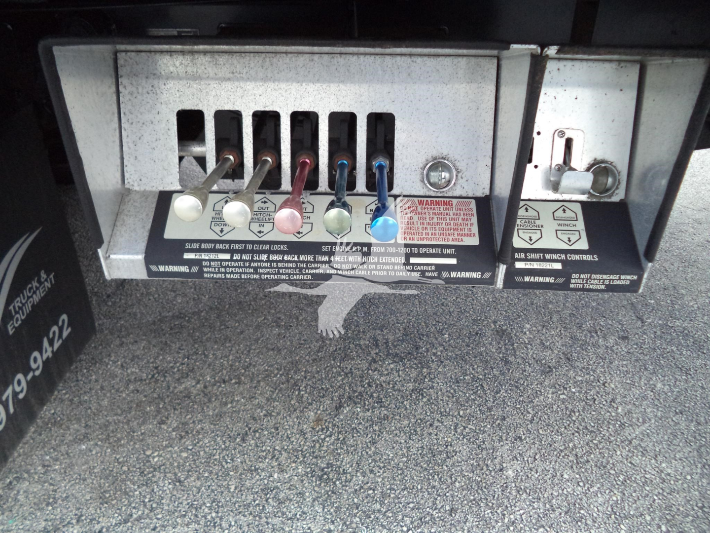 Peterbilt 348 rear electrical panel with multiple colored connectors and warning labels visible; series of levers and plugs under dashboard area.