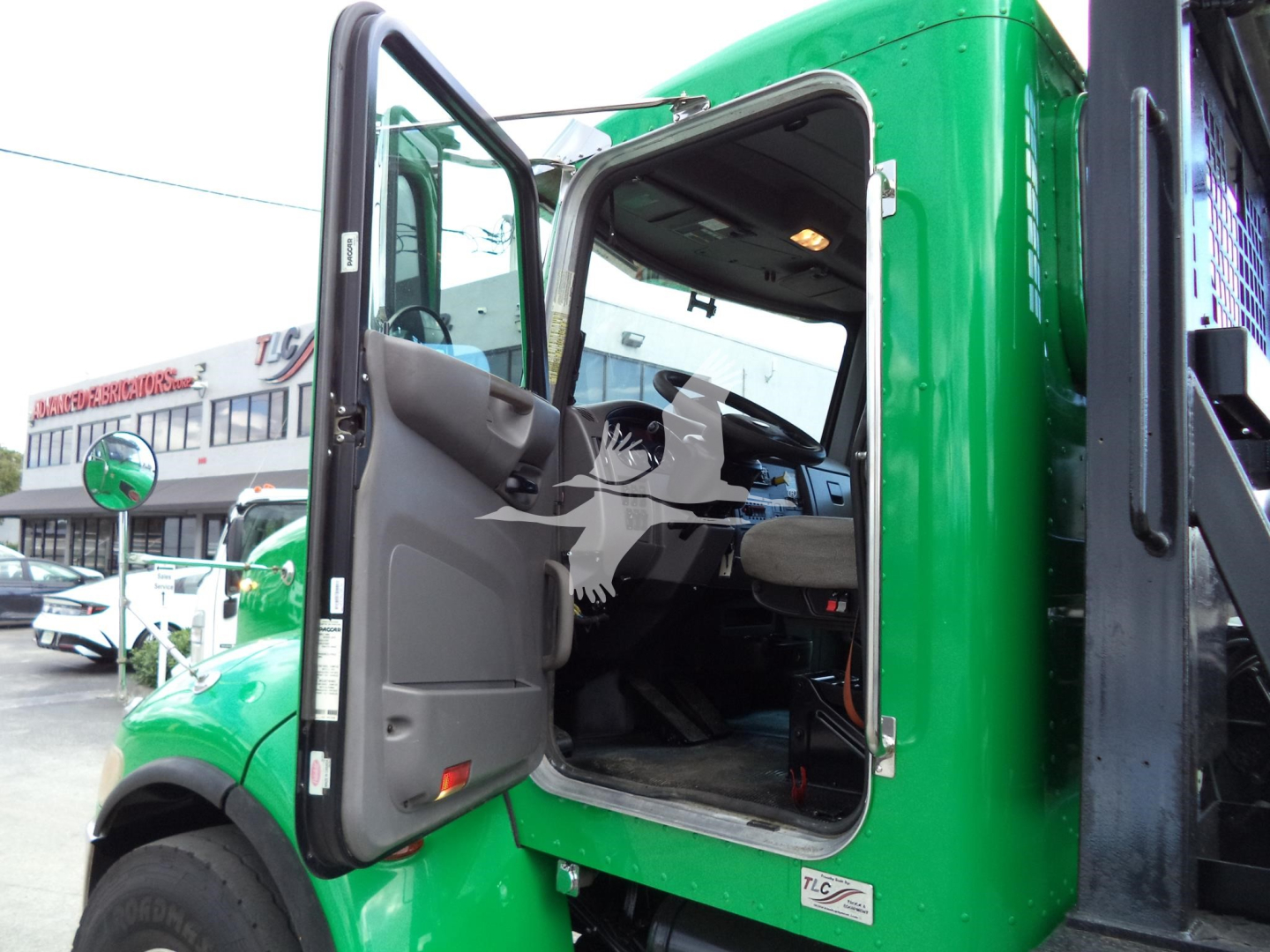 Peterbilt 348 rollback truck cab with open door, green exterior, showing interior dash and steering wheel.