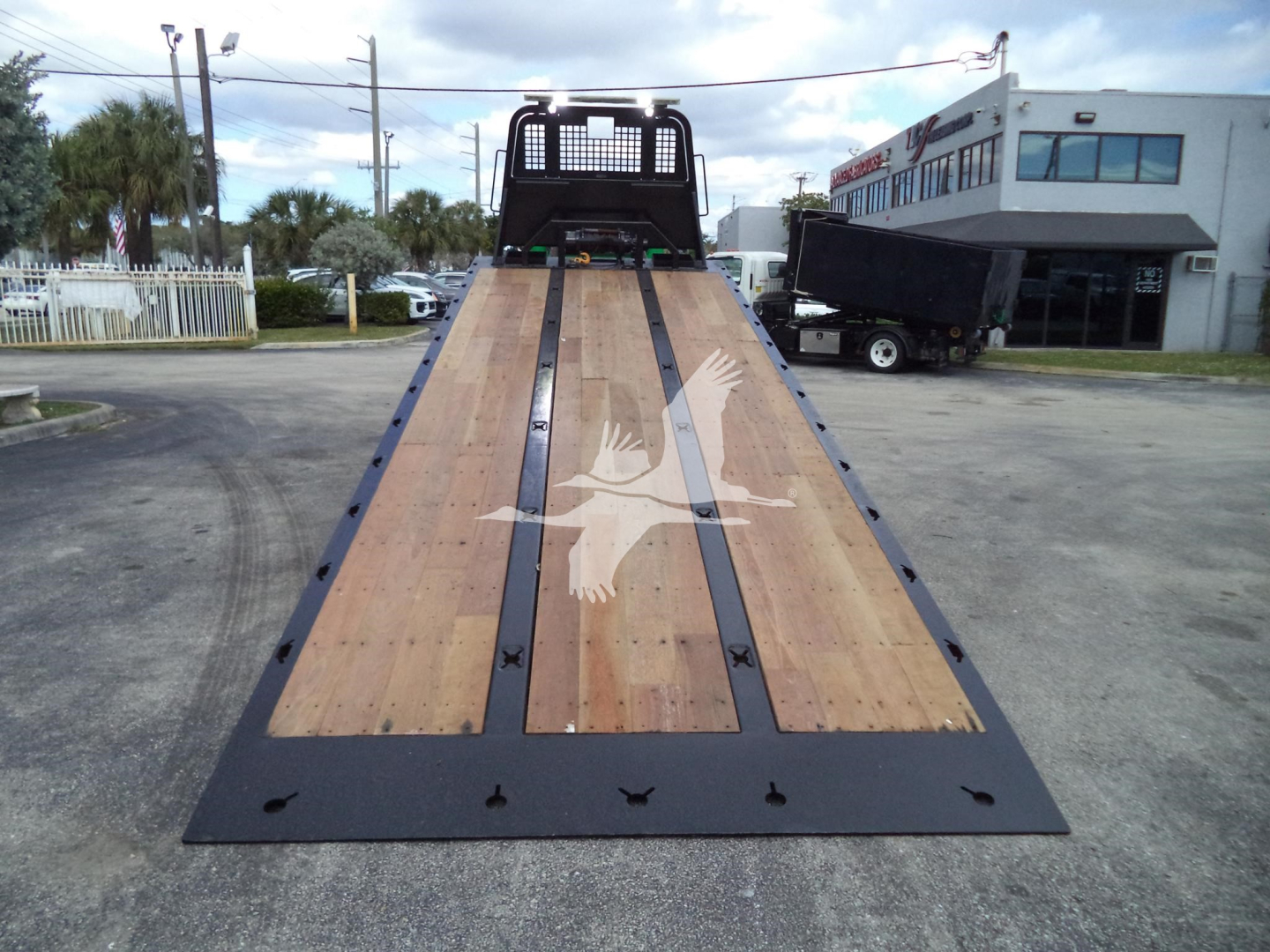 Peterbilt 348 rollback truck in loading position with wood-ribbed flatbed and loading ramp.