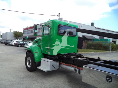 Green Peterbilt 348 rollback truck with crane arm, side view showing graphic white bird on cab door, chrome steps and fuel tanks.