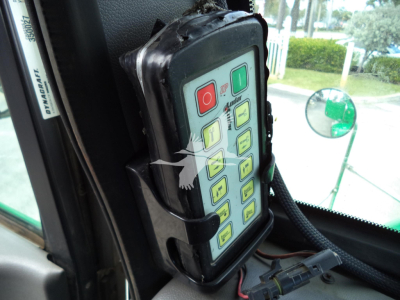 Peterbilt rollback truck interior control panel mounted on door with keypad and green rear view mirror visible.