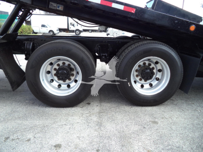 Peterbilt 348 rear dual-drive tires on a rollback truck chassis with wheel hubs and part of the dump bed frame visible.