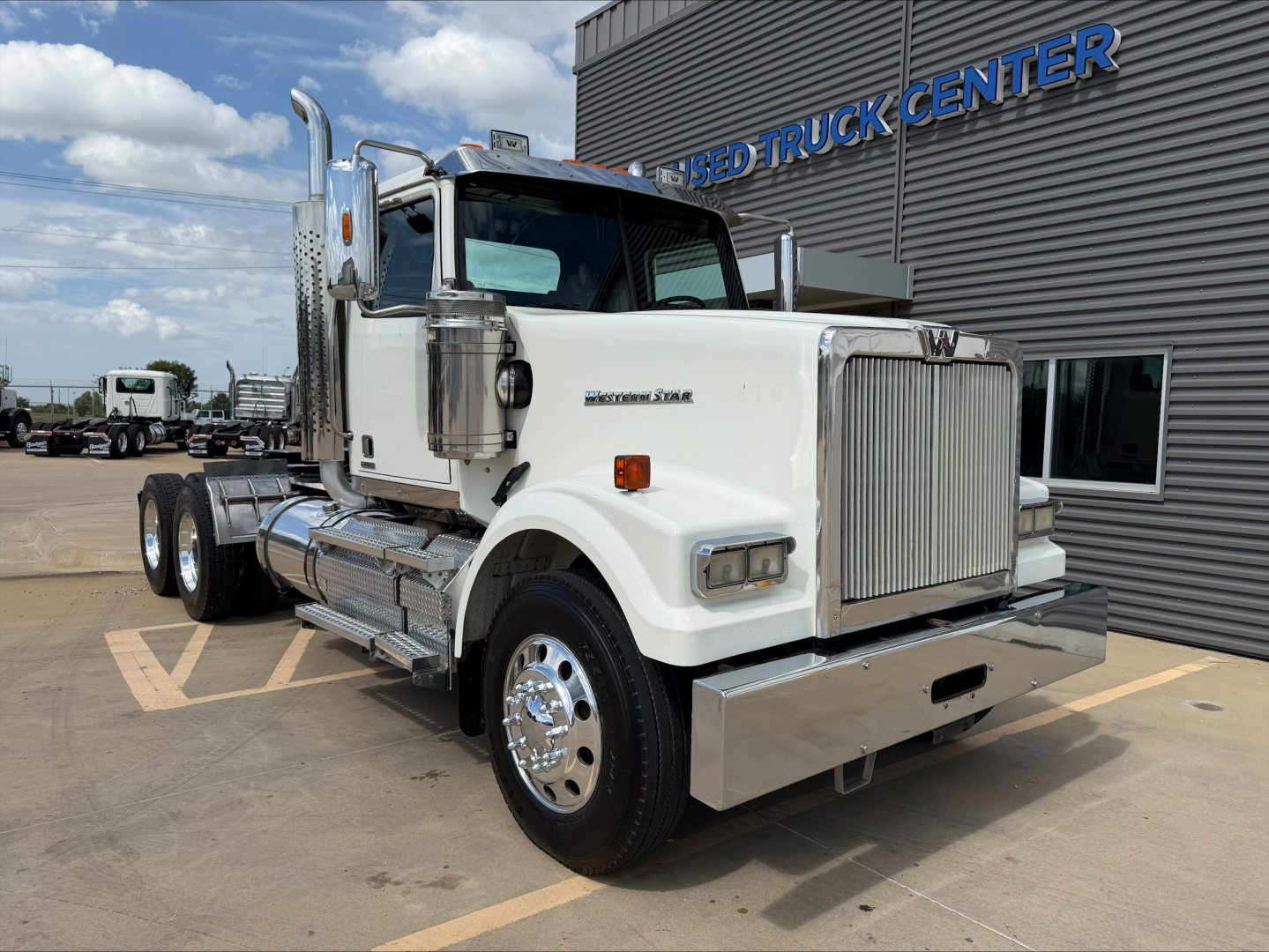 White 2019 Western Star 4900 SF conventional daycab truck parked outside dealership with chrome bumper, grille, and dual rear axles; visible VIN sticker and fuel tanks.