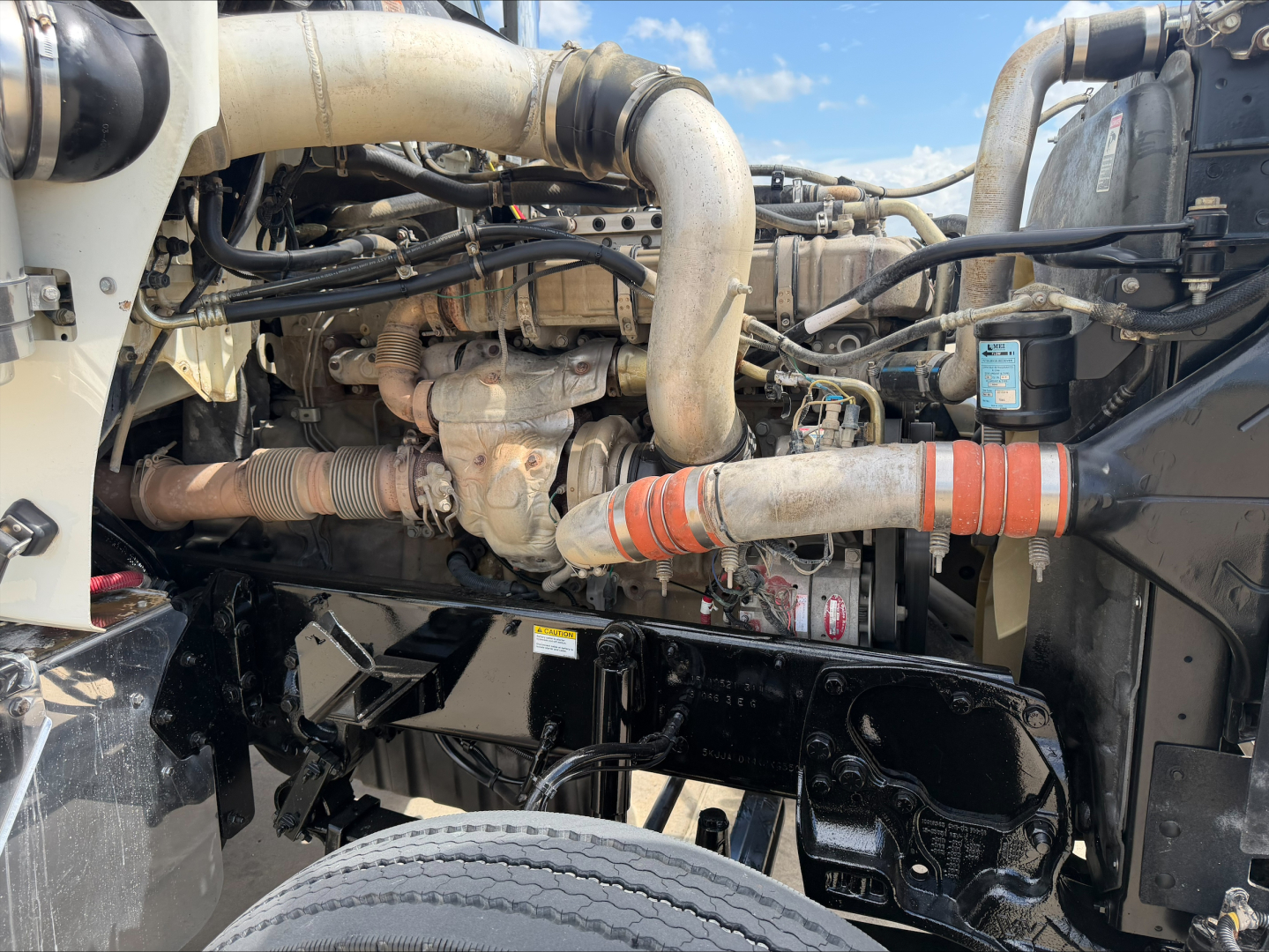 Engine bay of a 2019 Western Star 4900 SF conventional daycab showing intake and exhaust headers, hoses, and coolant/air lines; visible components include turbocharger, radiator hoses, and surrounding mechanicals.