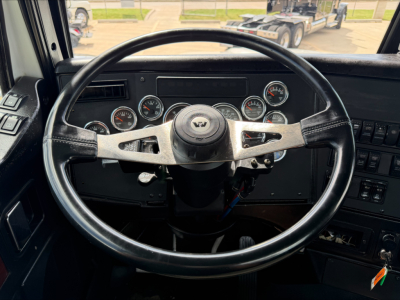 Truck cab dashboard with circular gauges and steering wheel seen from driver seat in a Western Star 4900 SF interior.