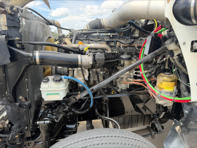 Western Star 4900 SF engine bay showing engine components, hoses, coolant reservoir, and yellow filter with colorful wiring.