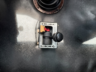 Trip switch panel with black toggle and yellow-red control on metallic surface, showing arrows and labels around it.