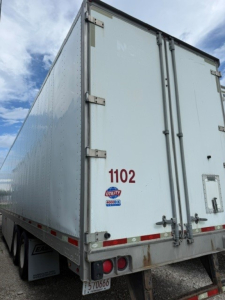 Rear view of a 2016 Utility 4000DX trailer showing rear doors, taillights, and bumper with unit number 1102 and safety decals.