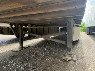 Underbelly of a utility trailer showing support legs, frame rails, and ground contact pads.