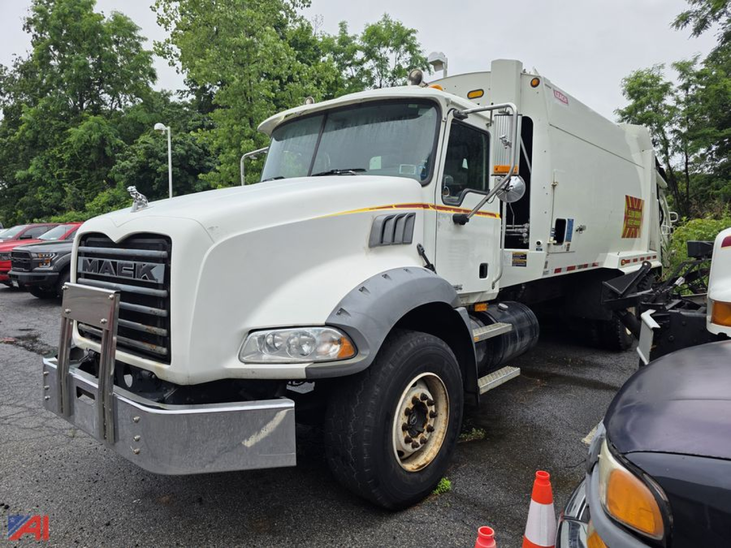 Front-left view of a white 2007 Mack Granite garbage truck with a large steel bumper guard and side mirrors; semi-truck cab, refuse body, and yellow warning stripe.