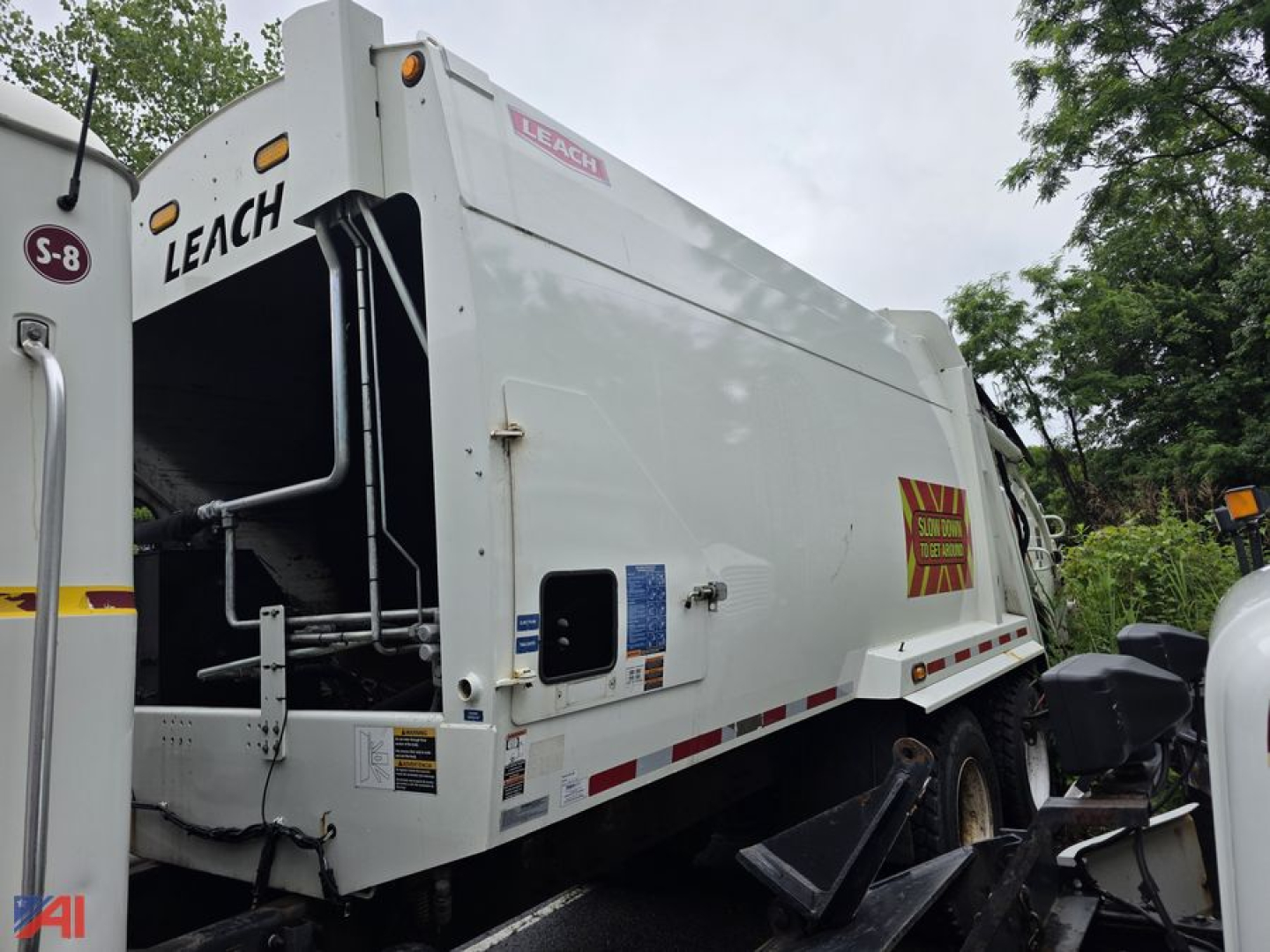 Mack Granite garbage truck rear and side view showing Leach rear loader compactor and warning decals in a used truck listing.
