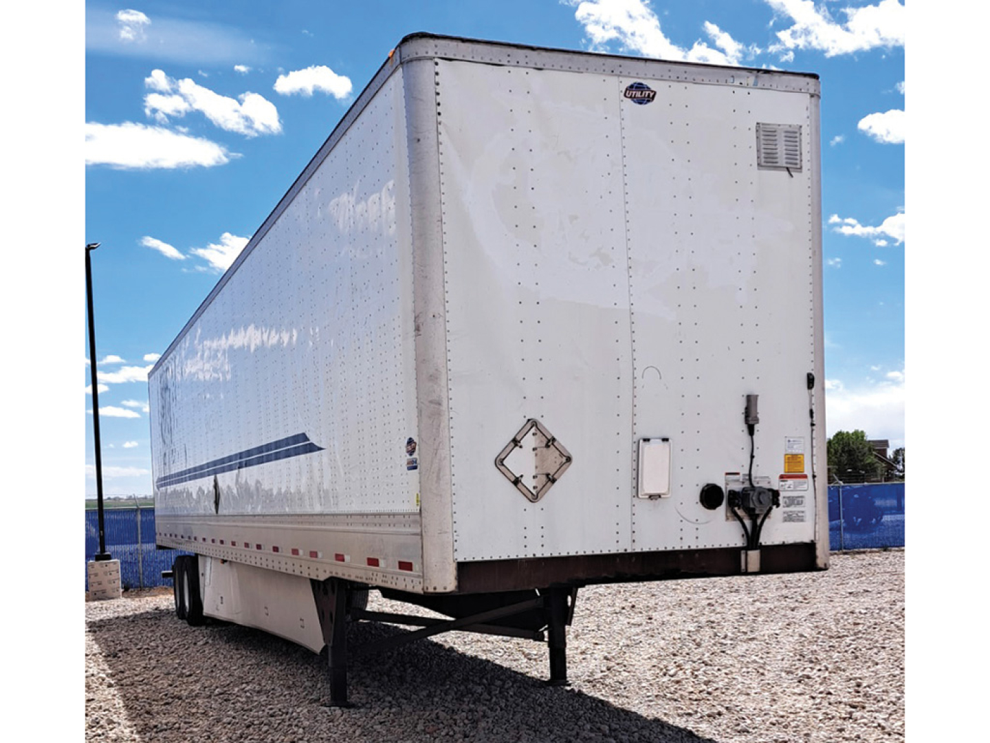 Utility 4000D-X tall bottom rail trailer in a storage lot showing rear and left side, with VIN and stock number not visible on the exterior.
