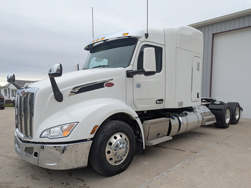 Peterbilt 579 UltraCab tractor truck side view showing chrome front bumper, fuel tanks, and sleeper cab.