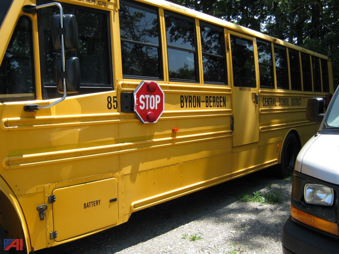 School bus side with STOP sign, BYRON-BERGEN Central School District markings, battery compartment door visible