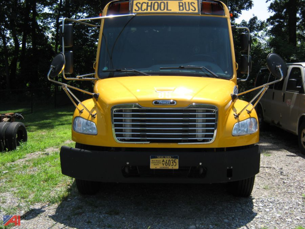 School bus front view showing yellow Freightliner C2 with large grille, front bumper, dual mirrors, and a 'SCHOOL BUS' sign on top; NY/NY license plate visible.
