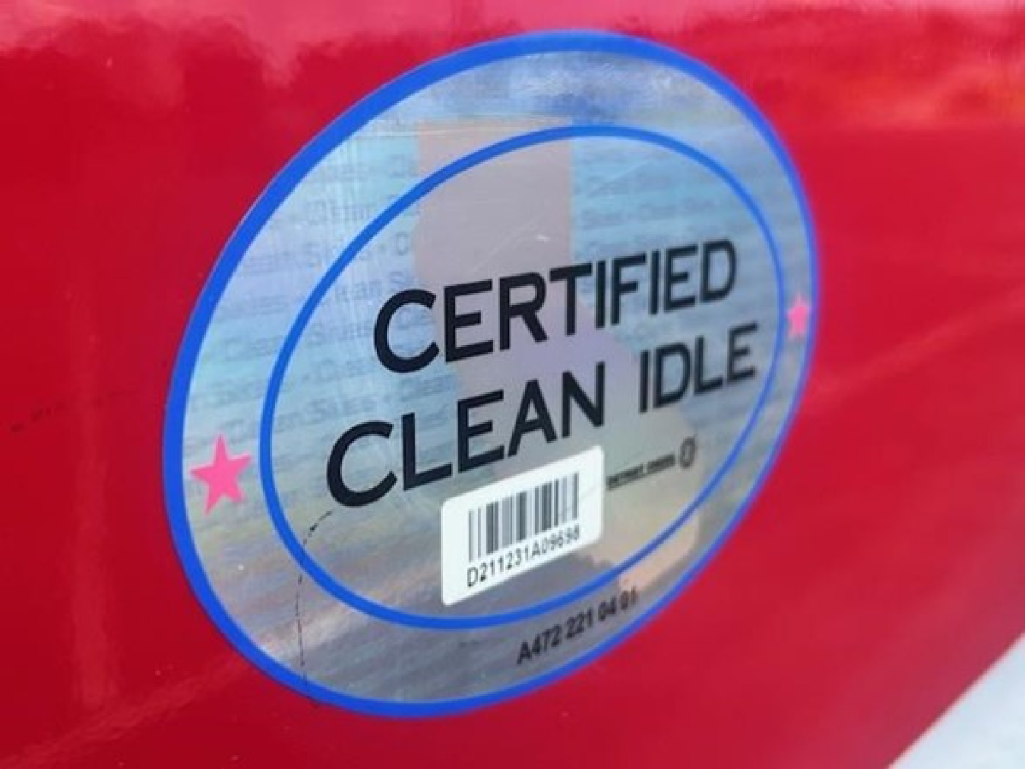 Certified Clean Idle badge sticker on red truck door with barcode and circular blue ring.