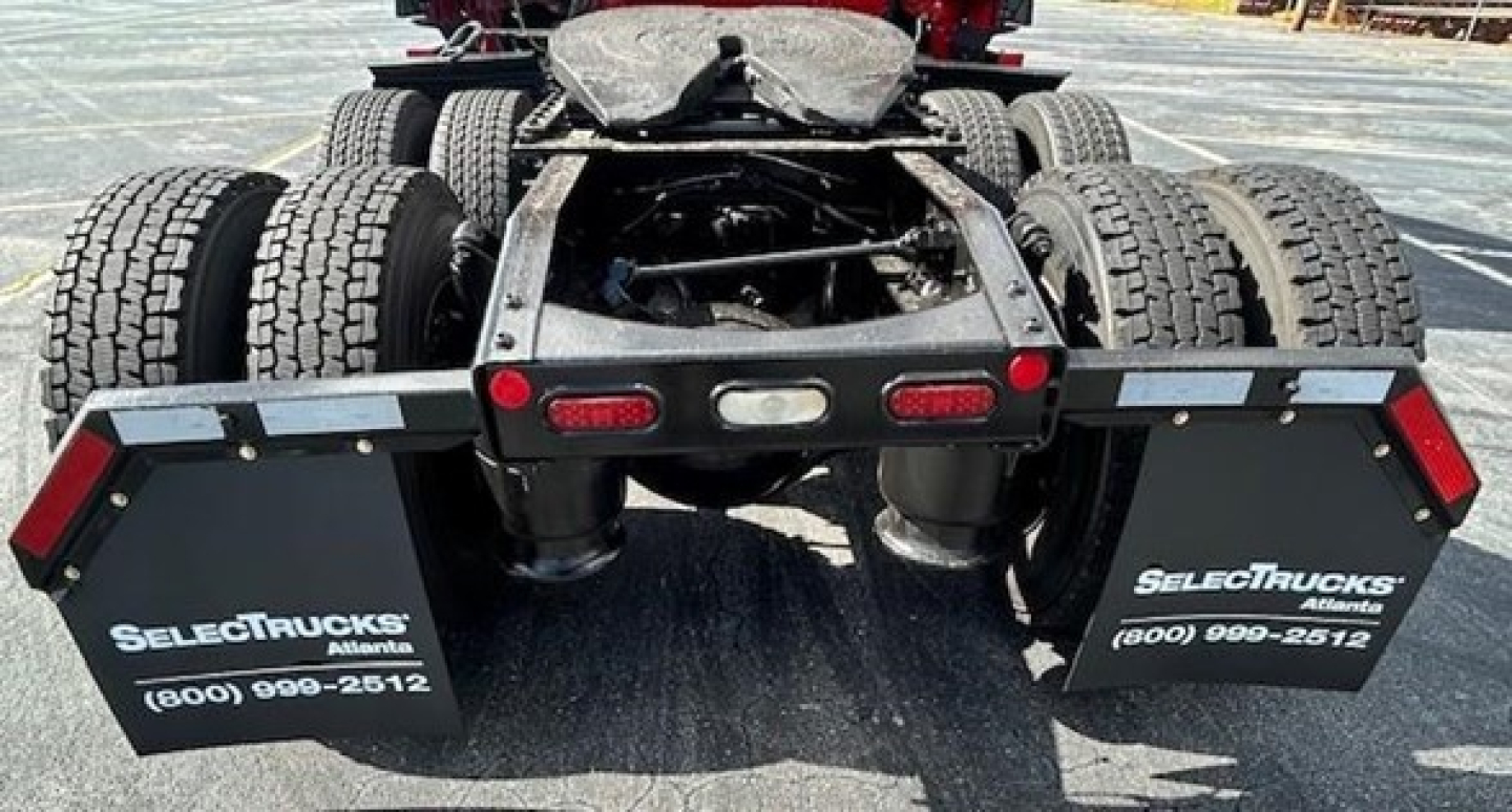 Rear view of a Freightliner Cascadia 126 truck chassis showing dual rear axles and mud flaps with SelectTrucks branding.
