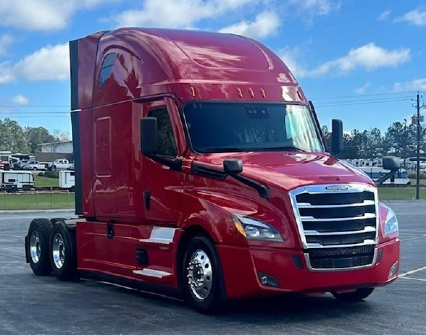 Freightliner Cascadia 126 truck in red, front three-quarter view, Sleeper cab, chrome grille, dual rear axles, clear sky.