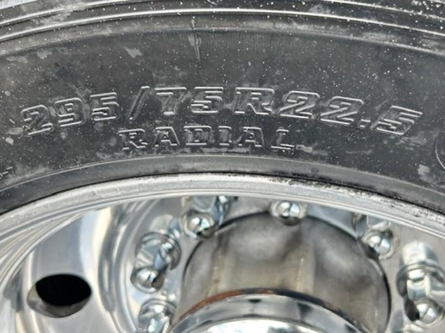 Tire and wheel area showing 235/75R22.5 radial tire on Freightliner Cascadia wheel.