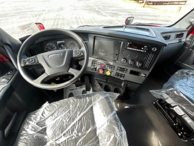 Freightliner Cascadia 126 cab interior view showing steering wheel, dashboard with touchscreen, gear shifter, and control panels.