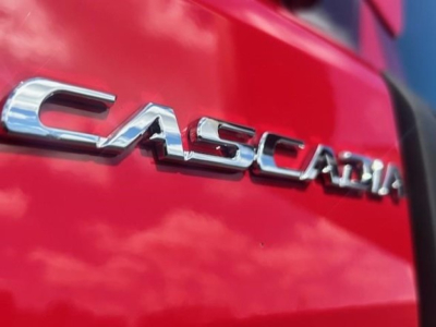 Cascia? Actually Freightliner Cascadia badge on red truck side showing chrome emblem 'CASCADIA'