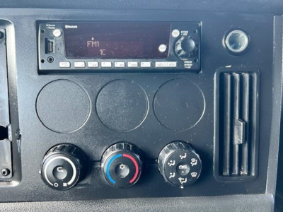 Dashboard panel of a Freightliner Cascadia showing radio/stereo unit, climate control knobs, and air vent.
