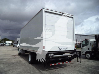 Box truck rear view showing cargo box and hitch, International MV; stock plate not visible; white box with reflective tape along bottom edge.