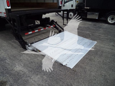 Truck flatbed ramp lowered showing aluminum platform and hydraulic lift with support structure in a used International MV truck bed area.