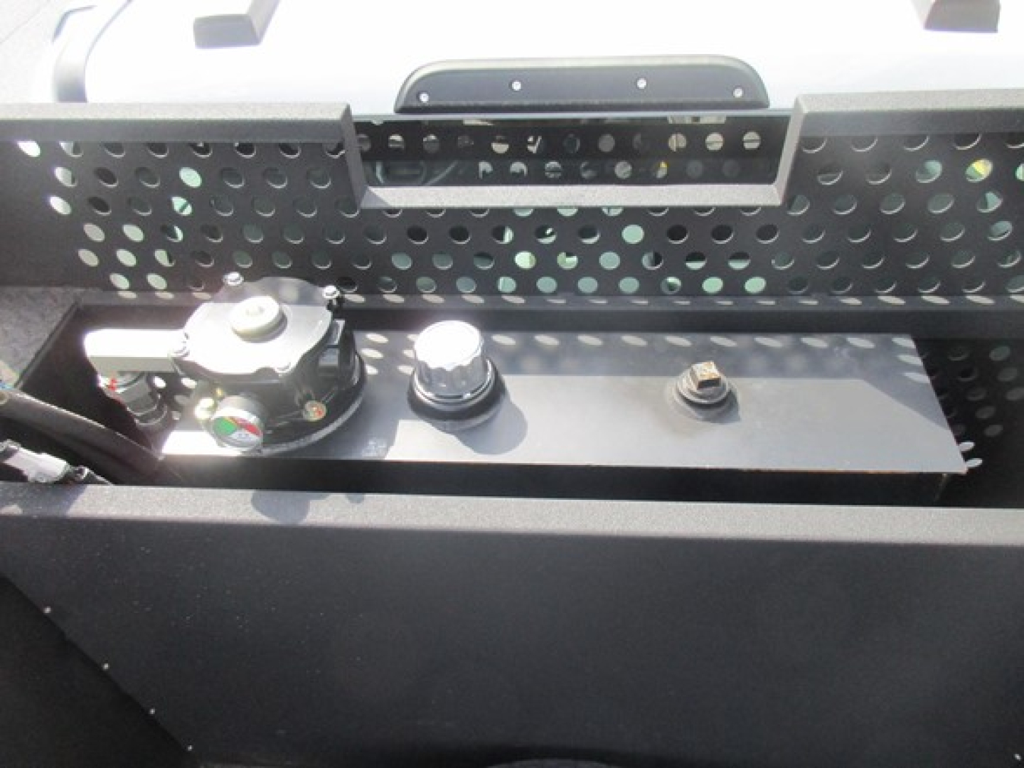 Ford F-550 service/utility truck battery area showing battery hold-down, terminals, and utility rack.
