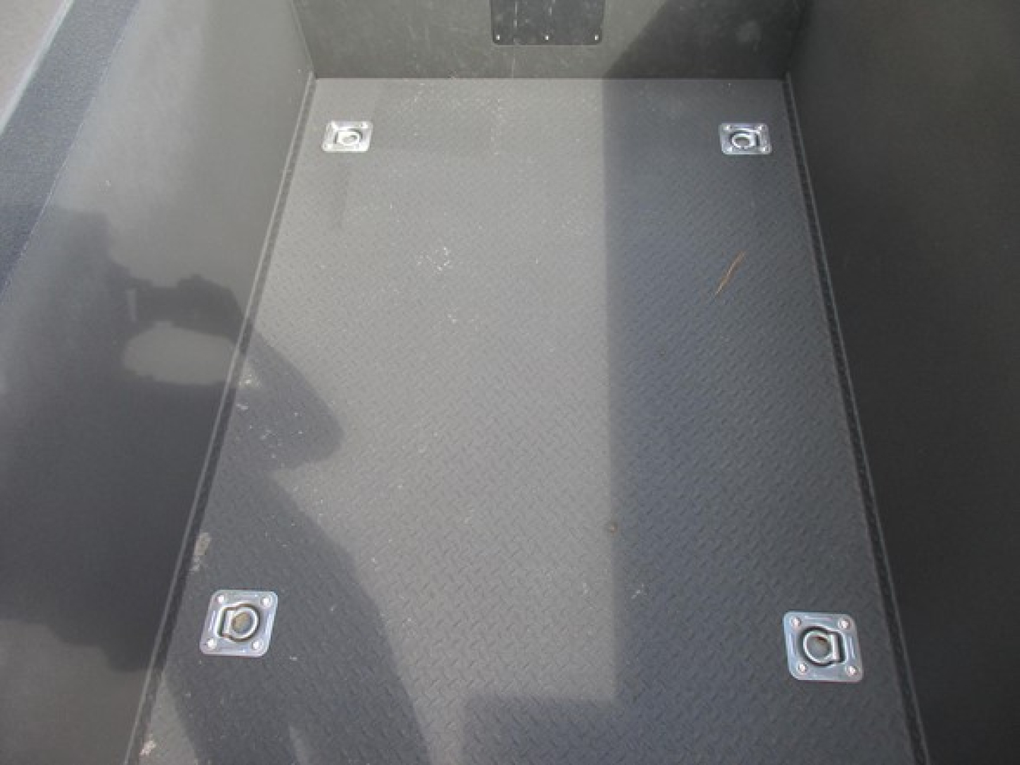 Ford F-Series service body cargo area floor with four tie-down rings and textured diamond plate surface.