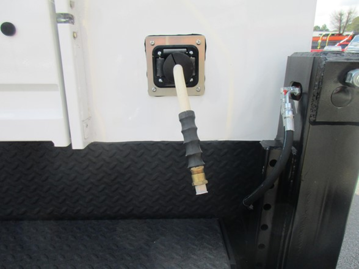 Ford F-550 service/utility truck image showing exterior fuel/refill connection with hose and nozzle port mounted on diamond-plate step area.