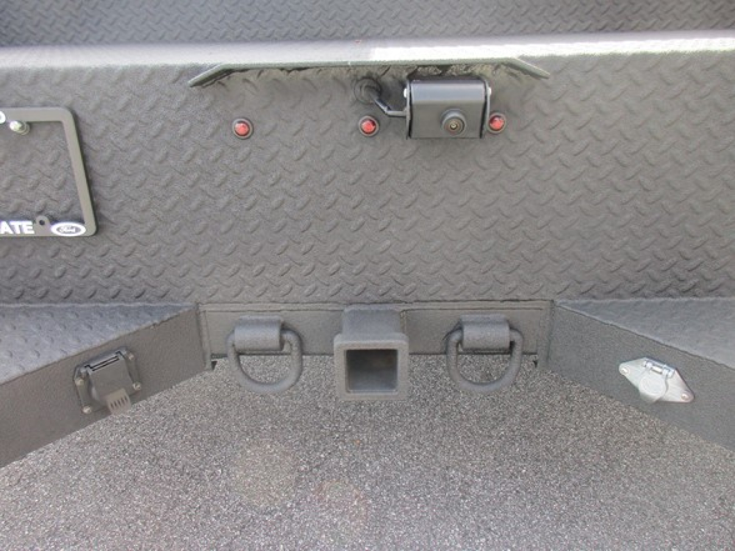 Ford F-550 service/utility truck rear view showing Diamond plate bed, hitch receiver, and tow hooks with metal latch.
