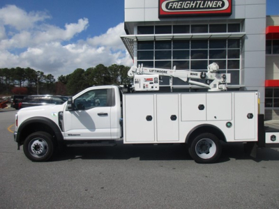 Ford F-550 service/utility truck with service body and crane, side profile view in dealership lot.