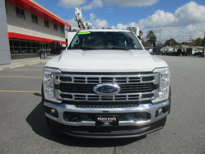 Ford F-550 front view in white with chrome grille and bumper, dealership plate. Visible Ford emblem on grille.