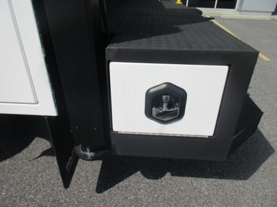 Ford F-550 service body step with quick-access storage box and lockable compartment showing sturdy metal structure.