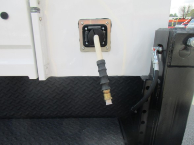 Ford F-550 service/utility truck image showing exterior fuel/refill connection with hose and nozzle port mounted on diamond-plate step area.