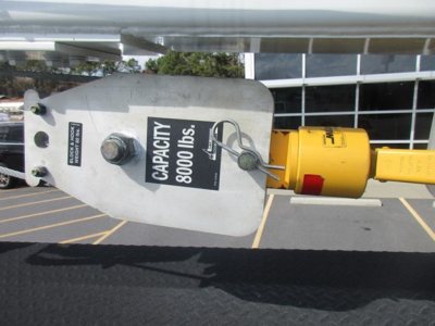 Auxiliary payload or tethered hook device with label 'CAPACITY 8000 LBS' and yellow electrical plug visible, mounted on a metal frame.