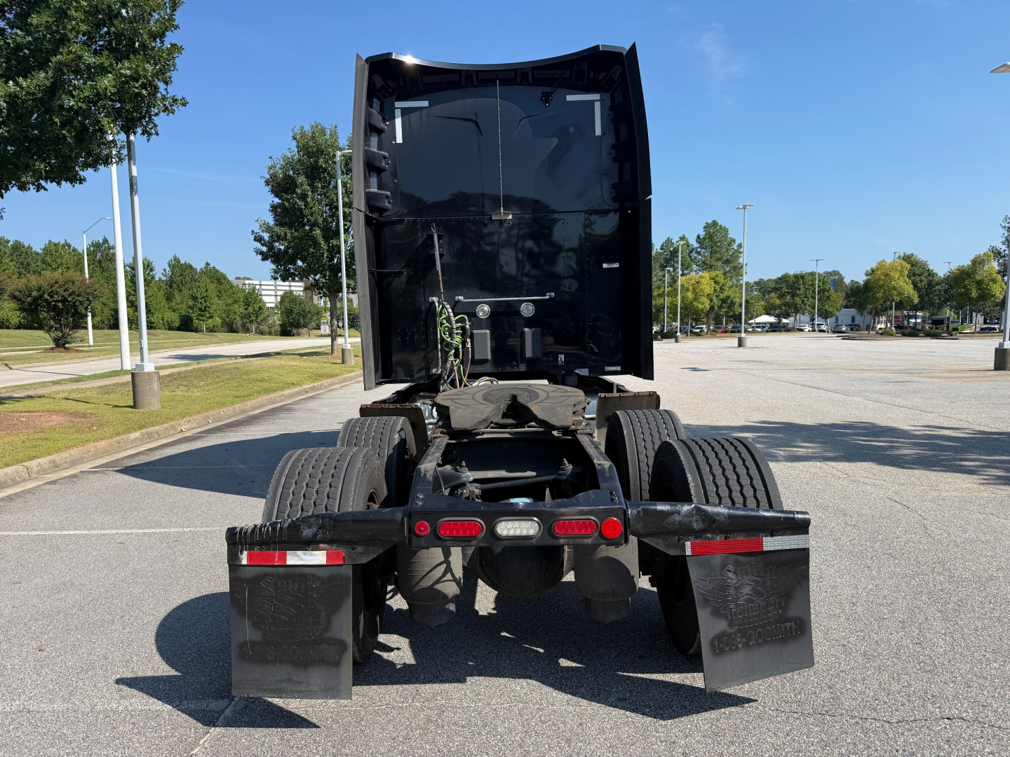 Peterbilt 579 tractor rear view showing chassis and dual rear axles, fifth wheel area, mud flaps, taillights, and U-shaped exhaust under sleeper cab.