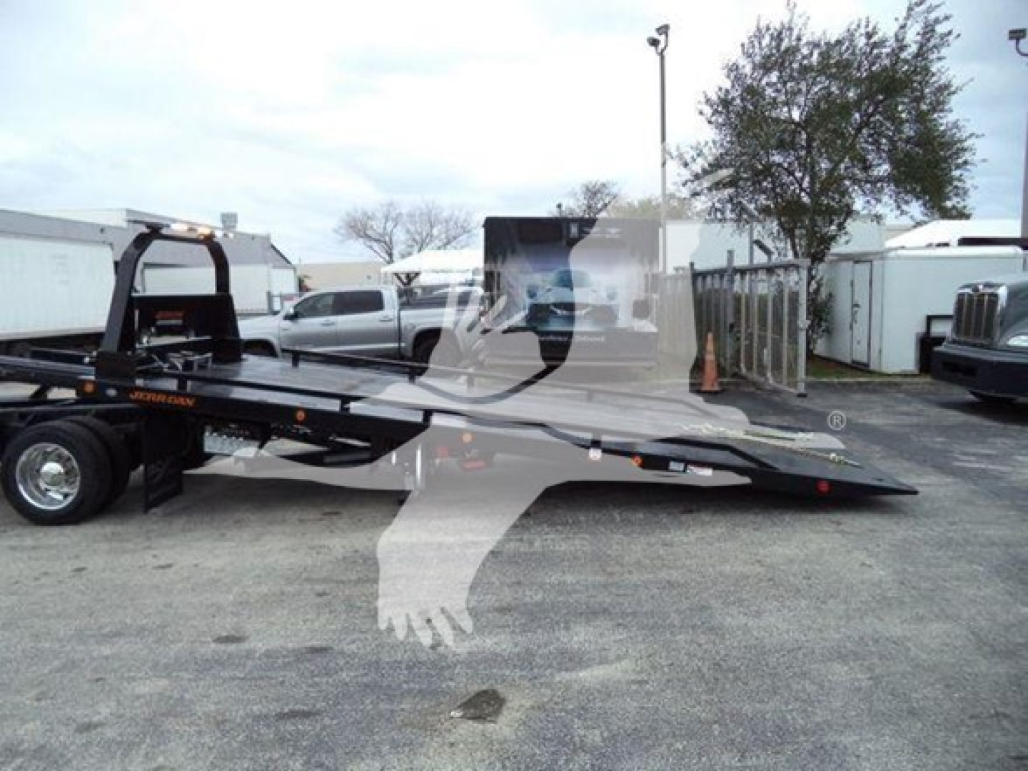 Low-angle view of a 2023 International CV rollback truck with a flatbed trailer and loading equipment in a dealership lot.