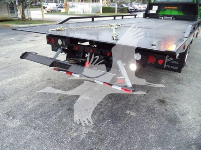 Truck bed of 2023 International CV rollback with flatbed and rear view showing taillights and towing equipment.