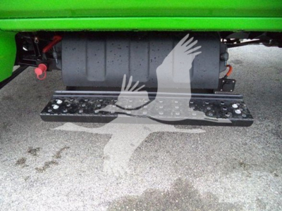 Inline view of a component on a 2023 International CV rollback truck showing a black metal transporter plate and welded footstep undercarriage.