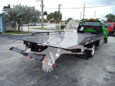 Flatbed tow truck with green cab showing alignment with ramp and hydraulic equipment