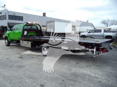 Green International CV rollback tow truck with flatbed and black chassis shown from rear-left side.
