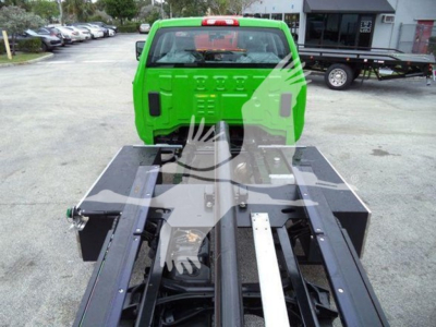 Truck chassis and green cab of a 2023 International CV rollback truck showing the frame and mounting mechanism for a heavy duty tow bed.