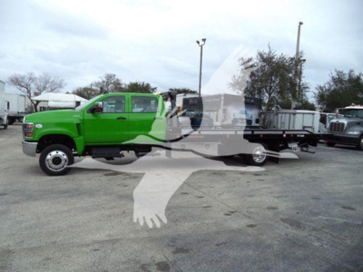2023 International CV rollback truck with bright green cab and black flatbed at a dealership lot.