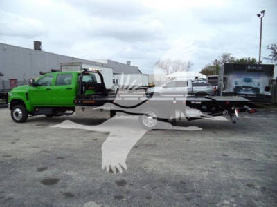 Green tow truck attached to a rollback wrecker, International CV, side view showing equipment and branding