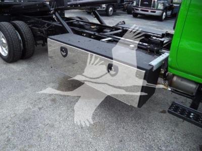 Truck chassis with a rectangular aluminum toolbox mounted behind the cab on a green International CV, showing the toolbox lid with two circular handles and a flatbed area.