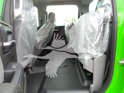 Truck cab interior with plastic-covered seats and spacious rear area, green exterior visible on the right.