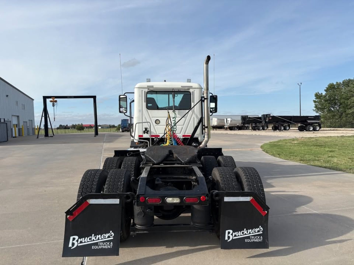 Rear view of a 2019 Mack Anthem daycab truck chassis with dual rear axles and mud flaps, showing spare tires and fifth wheel area.