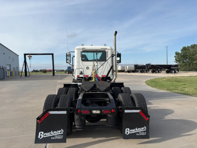 Rear view of a 2019 Mack Anthem daycab truck chassis with dual rear axles and mud flaps, showing spare tires and fifth wheel area.